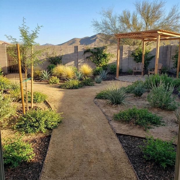 The same yard with a flagstone path, planted beds and a cedar ramada.